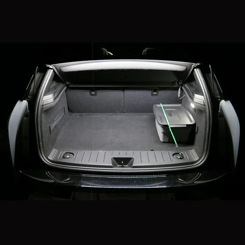 The open trunk of a BMW 3 Series (1990–2013) shows a gray storage bin with a green strap on the right, illuminated by the BMW 3 Series LED Interior Light Kit; the trunk is otherwise empty and clean.