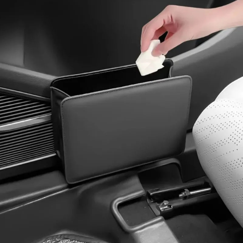 Car seat back storage box in use. Organizing essentials during detailing. Folds away compactly. Black mesh with metal hooks. 