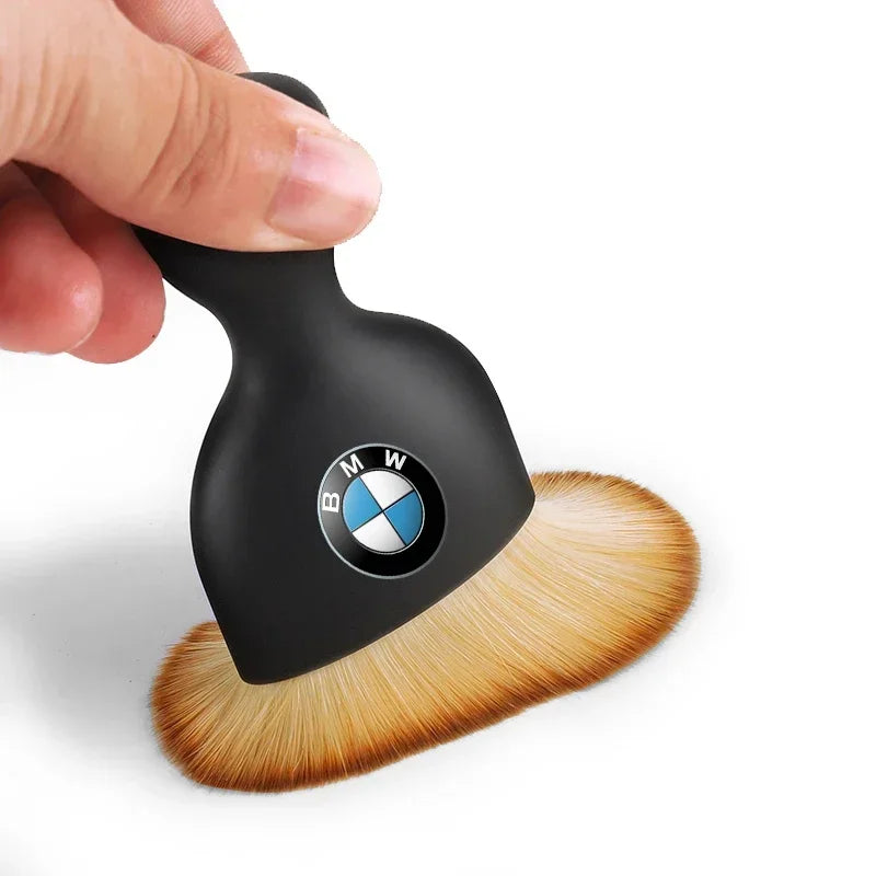 A hand holds a BMW-branded paintbrush against a plain background.