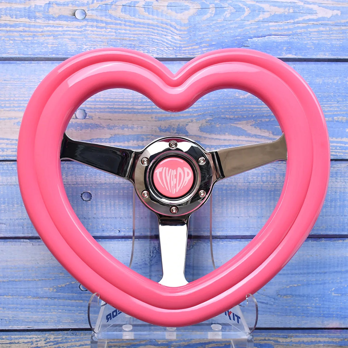 "Pink heart-shaped deep-dish steering wheel with embedded pink heart emblem."