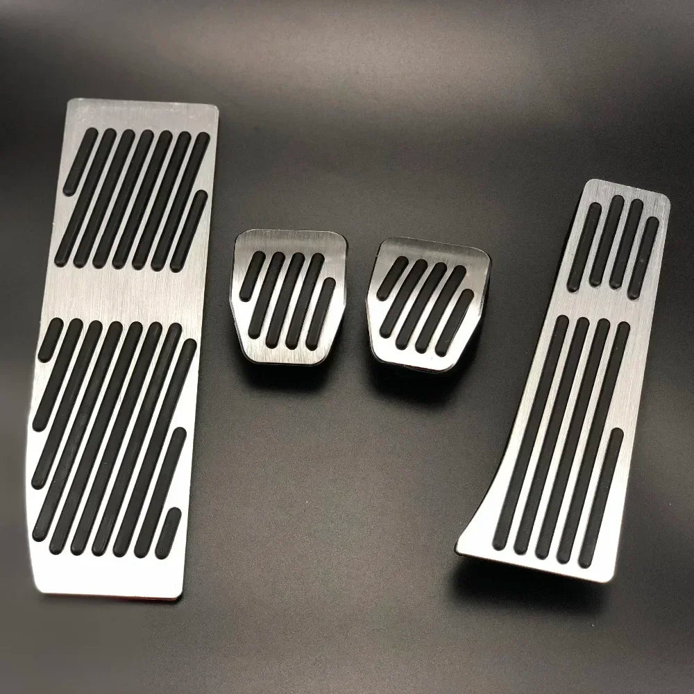 "Silver and black aluminum BMW pedal covers on a dark background."